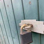 Padlock on a teal gate, commercial locksmith