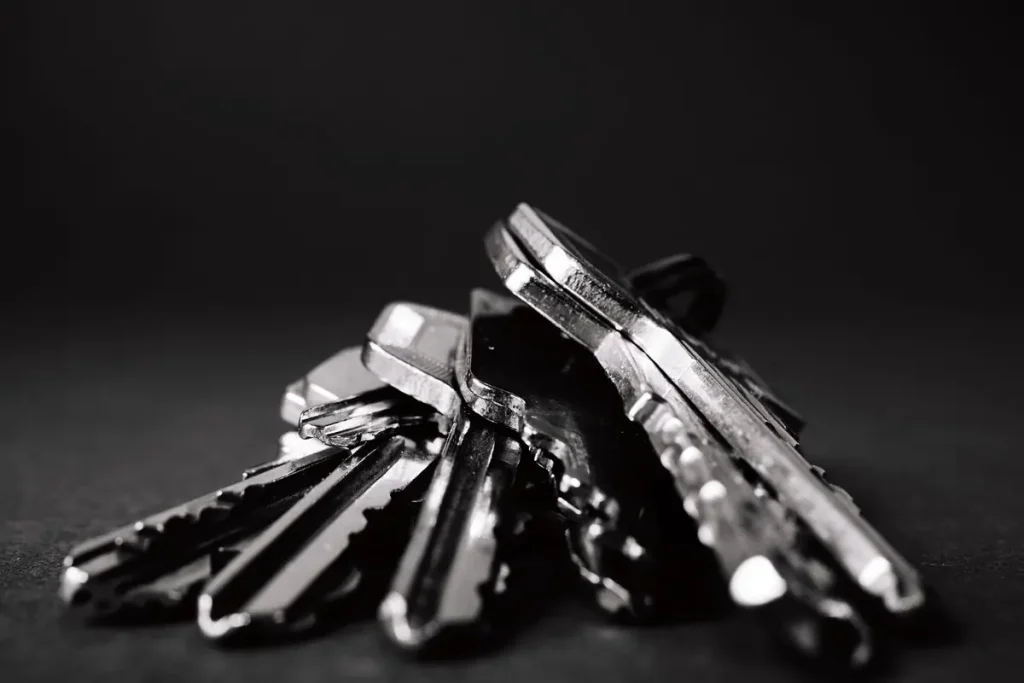 Pile of dark house keys on a black background, key cutting in Anderson, SC